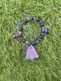 a purple bracelet with a tassel on the grass