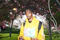 a man in a yellow hoodie holding a cell phone
