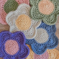 four crocheted flower coasters on a wooden table