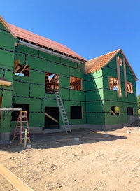 a house under construction with green siding and scaffolding