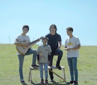 a group of young people posing in a field with guitars