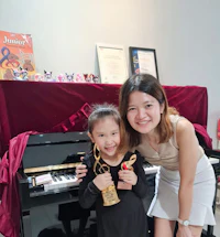 a woman and a little girl posing for a photo in front of a piano