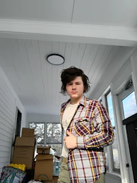a young man in a plaid shirt standing in a room