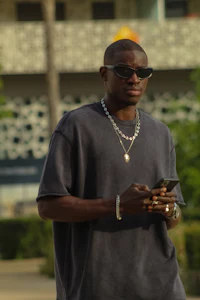 a man wearing sunglasses and a t - shirt is looking at his phone