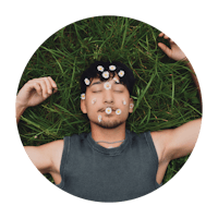 a man laying in the grass with flowers on his face