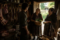 three people standing in a shack with meat on the counter
