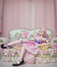 a doll sitting on a pink couch