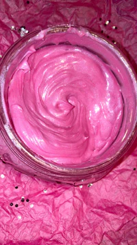 a bowl of pink icing sitting on top of a pink cloth