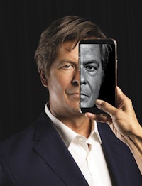 a man holding up a cell phone with a picture of a man on it