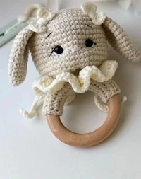 a crocheted bunny is holding a wooden ring