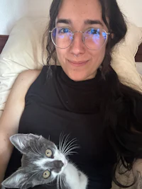 a woman with glasses laying on a bed with a cat