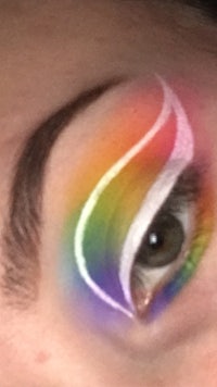 a close up of a woman's eye with a rainbow painted on it