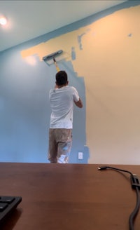 a man painting a wall in an office
