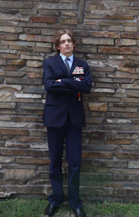 a man in a suit standing next to a brick wall