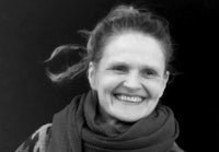 a black and white photo of a smiling woman wearing a scarf