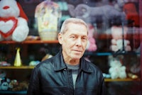 a man in a leather jacket standing in front of teddy bears