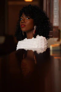 a black woman in a white dress is reflected in a mirror