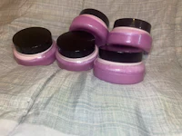four purple jars with lids sitting on a bed