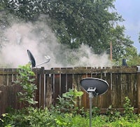 a satellite dish on a fence with smoke coming out of it