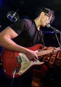 a young man playing an electric guitar in front of a microphone