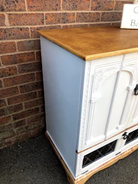 a white and gold sideboard in front of a brick wall