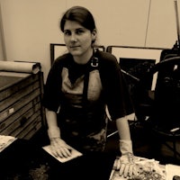 a black and white photo of a woman standing at a table