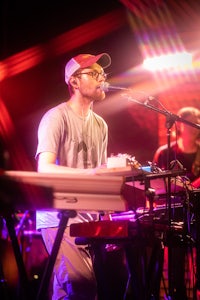 a man in a hat is playing a keyboard at a concert