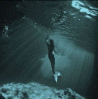 a mermaid swimming in a dark cave