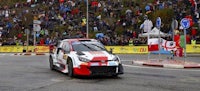 a rally car driving down a road in front of a crowd