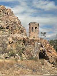 a stone tower sits on top of a rocky hill