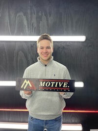 a young man holding up a sign that says motive