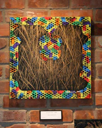 a colorful piece of art hanging on a brick wall