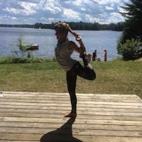 a woman doing a yoga pose on a wooden deck
