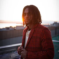 a man with dreadlocks standing on a rooftop