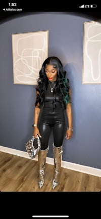 a woman in a black leather outfit standing in front of a wall