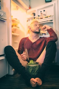 a man sitting on the floor in front of a refrigerator