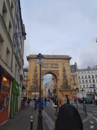 a person walking down a street with an arch in the background