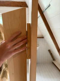 a person is holding a piece of wood in an attic