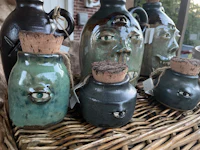 a group of jugs with faces on them on a wicker basket