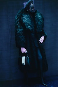 a woman in a black fur coat holding a handbag