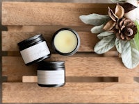 two jars of lip balm sitting on a wooden table