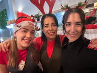 three women posing for a photo with santa claus hats