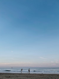 two people flying kites on the beach at dusk