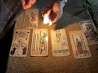 a person lighting a candle next to a group of tarot cards