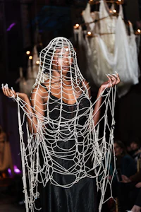 a woman wearing a dress covered in spider webs on a runway