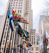 a group of flags flying in front of tall buildings