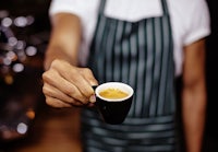 a barista holding a cup of coffee