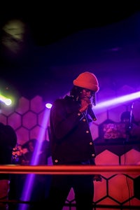 a man in a hat on stage in front of a purple light