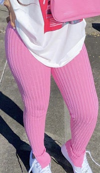 a woman wearing pink ribbed leggings and white sneakers