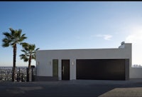 a modern home with a garage and palm trees